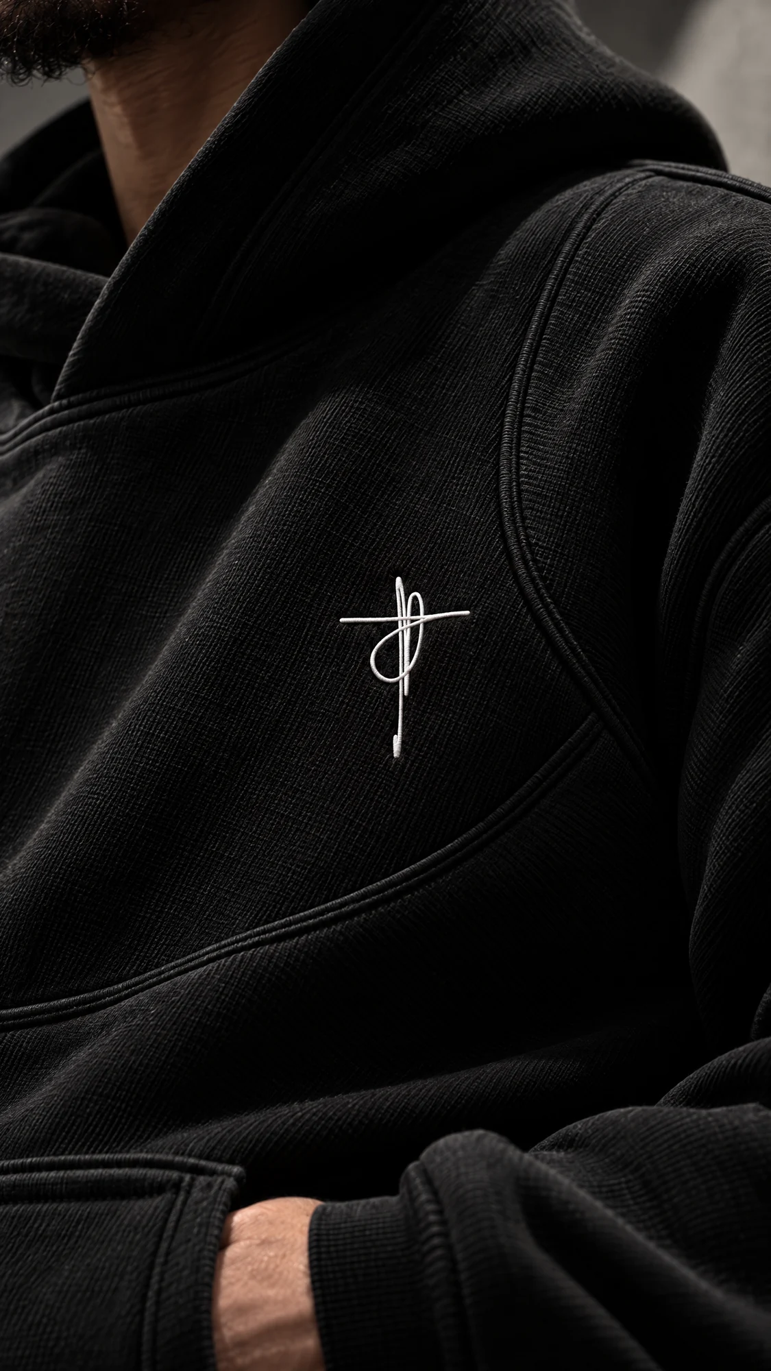 White XAUNI embroidery and a curved seam on black hoodie fabric