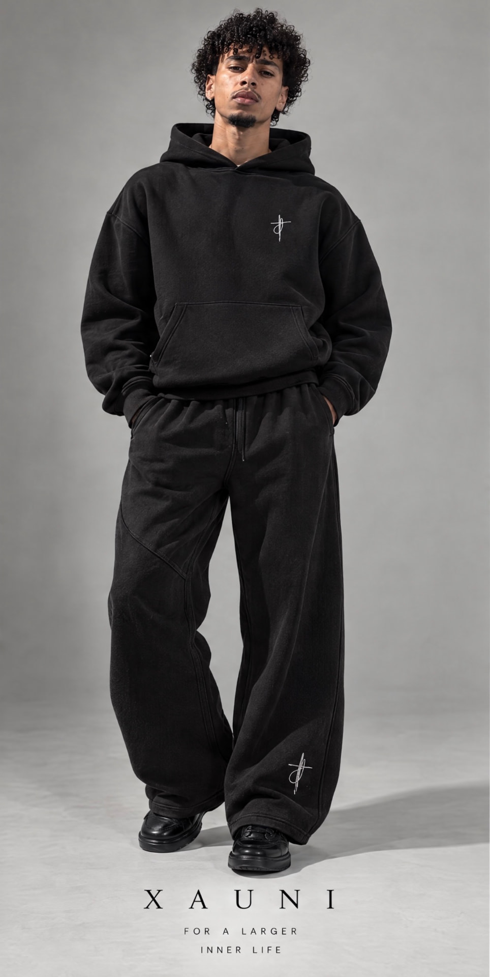 Black XAUNI boxy hoodie styled with wide-leg black trousers, with the full XAUNI caption visible